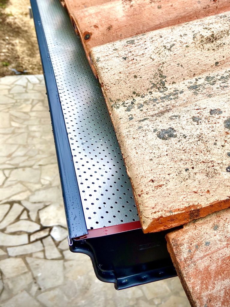 Pose de grilles pares feuilles sur une gouttière corniche de couleur bleu ardoise.